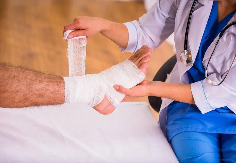 A clean dressing being wrapped around the foot